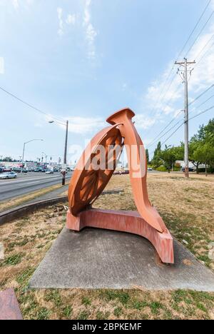 La sculpture de Fritz Church, la "Gateway", est la grande roue orange sur South Tacoma Way à Tacoma, Washington. Il repose sur deux pointes stylisées de chemin de fer. Banque D'Images