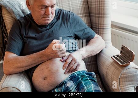 Man avec le diabète est l'injection de l'insuline dans son ventre à la maison. Banque D'Images