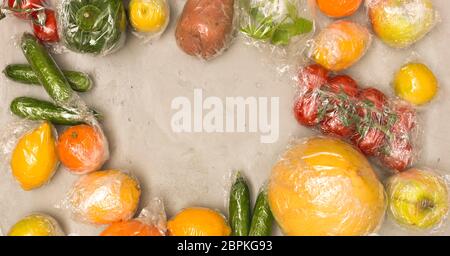 Beaucoup de différents fruits et légumes sont emballés dans un sachet en plastique, paniers sur fond de béton Banque D'Images