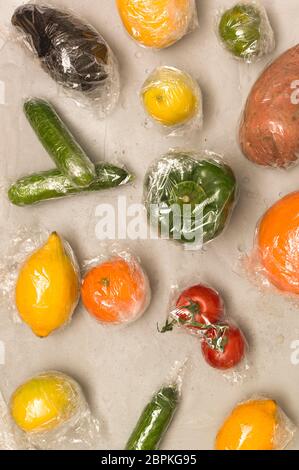 Beaucoup de différents fruits et légumes sont emballés dans un sachet en plastique, paniers sur fond de béton Banque D'Images