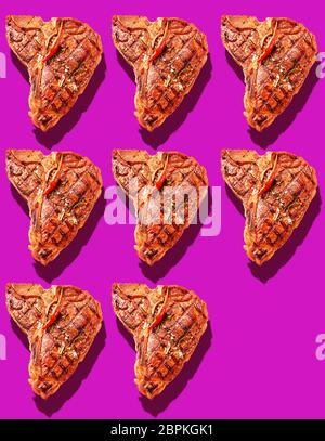 Huit mariné grillé T-bone steaks avec hot red chili pepper garnir sur fond magenta vif avec copie espace et des ombres portées Banque D'Images