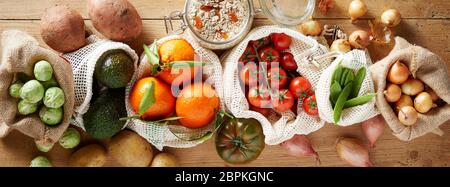 Assortiment de légumes biologiques frais vus du dessus sur fond de bois, paniers en tissu réutilisables sacs respectueux de l'environnement. L'épicerie du marché local b Banque D'Images