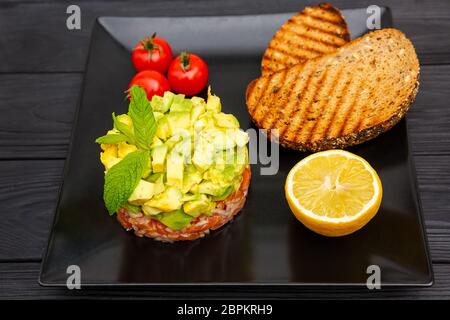 Sandwich avec tranches d'oignon et avocat sur fond noir en bois Banque D'Images