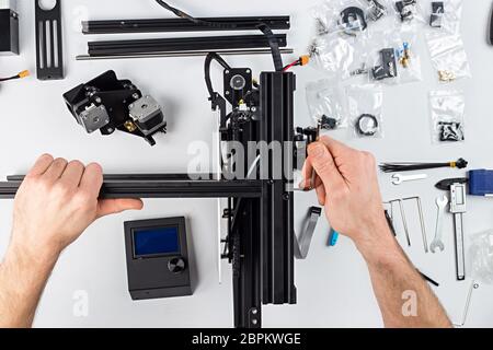 Jeune homme assemblée étudiante de imprimante 3D kit sur fond de table blanc Banque D'Images