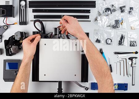 Jeune homme assemblée étudiante de imprimante 3D kit sur fond de table blanc Banque D'Images