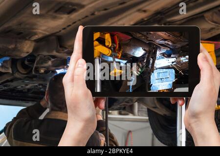 Concept de voyage - photographies de souder le silencieux du véhicule par soudure à l'argon au cours de la réparation en atelier sur smartphone Banque D'Images