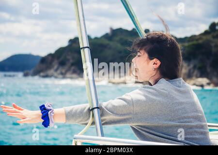 Une adolescente exprime sa joie émotionnellement et profite de vacances de printemps dans un voyage en mer sur un bateau de plaisance. Banque D'Images