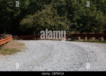 Pont de fer rouillé garde-corps sur une route de gravier Banque D'Images