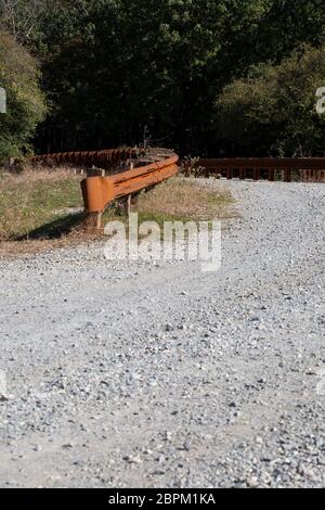 Pont de fer rouillé garde-corps sur une route de gravier Banque D'Images