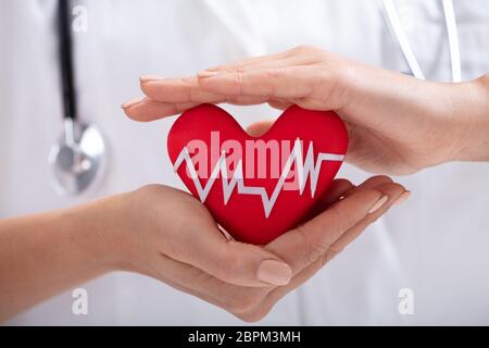 Close-up of Woman's hand protection en forme de coeur rouge avec pouls battre blanc Banque D'Images