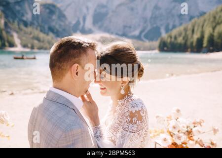 Les jeunes mariés baissent sur place pour la cérémonie, avec une arche de colonnes de fleurs d'automne, sur fond de Lago di Braies en Italie Banque D'Images