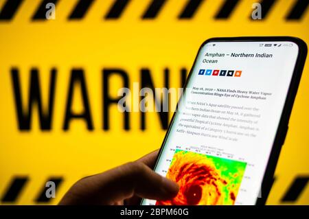 Jaipur, Inde, Circa 2020 - photo d'un téléphone mobile avec cyclone se déplaçant vers la côte. L'arrière-plan est jaune et comporte un signe d'avertissement Banque D'Images