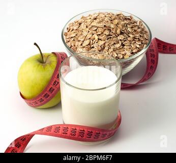 Produits de régime pomme verte, verre avec le kéfir et le gruau imbriquées dans la bande de mesure isolé sur fond blanc Banque D'Images