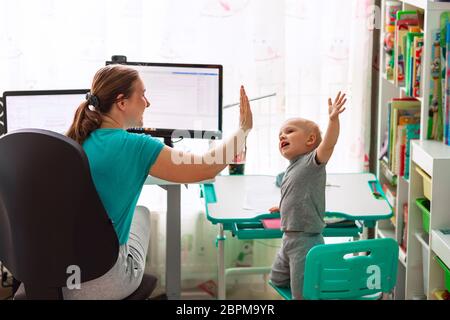 Mère avec enfant essayant de travailler de la maison pendant la quarantaine. Rester à la maison, travailler à domicile concept pendant la pandémie de coronavirus Banque D'Images