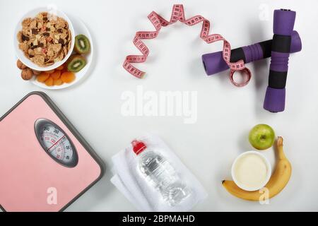 La forme physique féminine reste la vie. Aliments sains, balances et accessoires de sport sur fond blanc. Vue de dessus avec espace de copie. Fitness, sport et santé li Banque D'Images