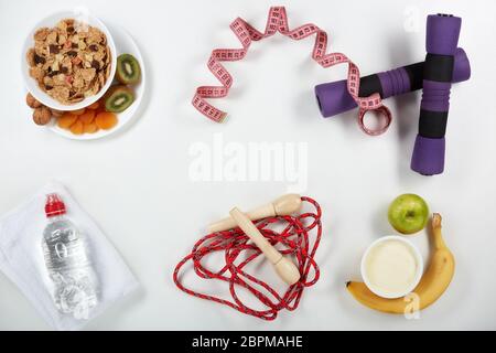 La forme physique féminine reste la vie. Aliments sains, ruban de mesure et accessoires de sport sur fond blanc. Vue de dessus avec espace de copie. Fitness, sport et lui Banque D'Images