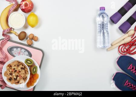 La forme physique féminine reste la vie. Aliments sains, balances et accessoires de sport sur fond blanc. Vue de dessus avec espace de copie. Fitness, sport et santé li Banque D'Images