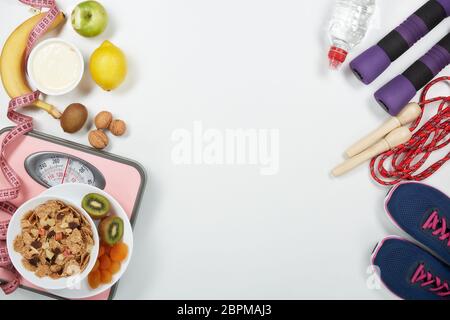 La forme physique féminine reste la vie. Aliments sains, balances et accessoires de sport sur fond blanc. Vue de dessus avec espace de copie. Fitness, sport et santé li Banque D'Images