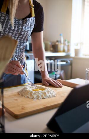 Anonyme personne faisant des pâtes fraîches à la maison dans la cuisine, regardant UN portrait de recette vidéo Banque D'Images