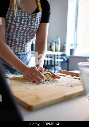 Anonyme femme faisant de la pâte fraîche à la maison dans sa cuisine sur bois. Banque D'Images