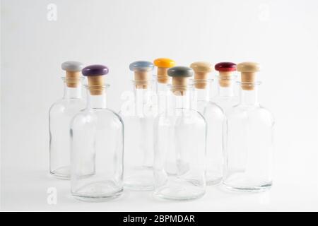 petits flacons en verre vides avec bouchon coloré sur une surface blanche Banque D'Images