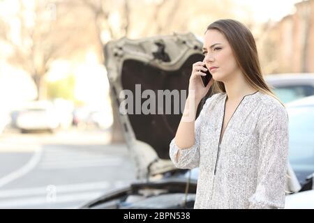 Conducteur sérieux avec une voiture en panne sur l'assurance-appelant téléphone dans la rue Banque D'Images