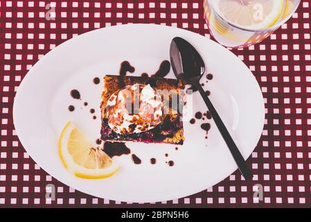 Gâteau maison avec fruits de la forêt servi sur une assiette avec un verre de limonade rafraîchissante avec une tranche de citron Banque D'Images