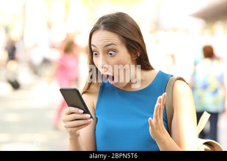 Surpris woman receiving nouvelle choquante sur un téléphone intelligent dans la rue Banque D'Images