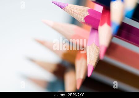 Macro-vision des pointes de crayon de couleur empilés devant un fond blanc avec une faible profondeur de champ. Banque D'Images