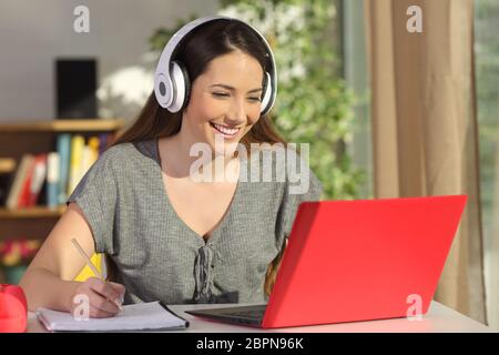 Magnifique portrait d'une ligne sur l'apprentissage des élèves regardant la vidéo tutoriaux avec un ordinateur portable et un casque rouge dans un tableau à la maison Banque D'Images