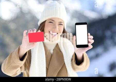 Portrait en vue avant d'une femme montrant une carte et un écran de téléphone dans une montagne enneigée en hiver Banque D'Images