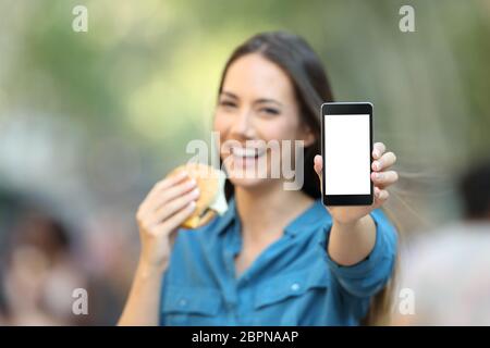 Femme tenant un burger montrant un écran de téléphone des maquettes sur rue Banque D'Images