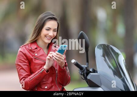 Heureux à l'aide d'un smart phone motorbiker assis sur une moto Banque D'Images