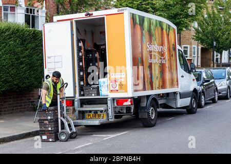 Un liveur de Sainsbury déchargeant ses achats de sa camionnette sur le côté de la route pendant le confinement en cas de pandémie du coronavirus, Londres, Royaume-Uni Banque D'Images