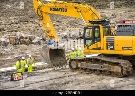 PORTHCAWL, PAYS DE GALLES - JUIN 2018 : pelle hydraulique à Porthcawl livrant du béton mélangé prêt aux travailleurs le réaménagement du front de mer Banque D'Images