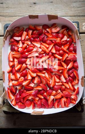 Préparation du gâteau éponge avec de la crème et des fraises Banque D'Images