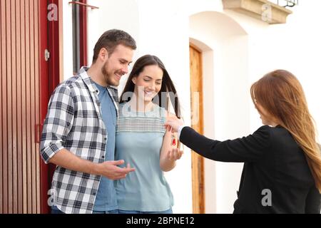 Couple heureux de recevoir les clés de la maison de l'agent immobilier Banque D'Images