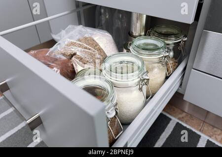 Différentes graines dans des bocaux de stockage à hutch, cuisine moderne blanc en arrière-plan. Organisation Smart Kitchen Banque D'Images