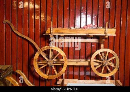 Chariot rustique en bois à quatre roues . oignon dans des sacs en bois pour chariot . Bois de wagon. Transport de l'ancienne ferme. Ancien cargo sur fond de bois rouge Banque D'Images