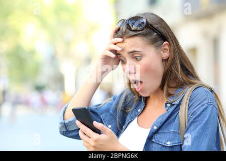 Choqué adolescente contrôle smart phone découvrir contenu erreur dans la rue Banque D'Images