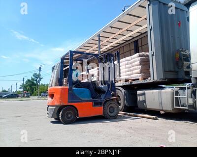 Krasnodar, Russie - 13 juin 2019 : déchargement de sacs de ciment d'un camion avec un chariot élévateur. Banque D'Images