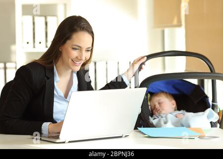 Heureuse mère célibataire travaillant sur la ligne et prendre soin de son bébé à l'office de tourisme Banque D'Images