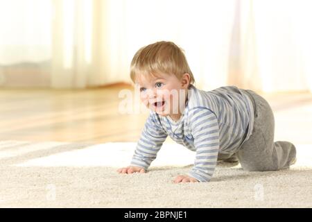 Happy Baby crawling et de rire sur un tapis à la maison avec une lumière chaude dans l'arrière-plan Banque D'Images