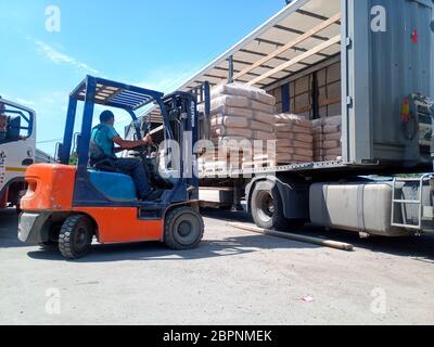 Krasnodar, Russie - 13 juin 2019 : déchargement de sacs de ciment d'un camion avec un chariot élévateur. Banque D'Images