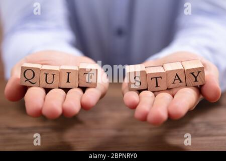 Close-up Man's Hand Holding quitter et rester sur les blocs de bureau en bois Banque D'Images