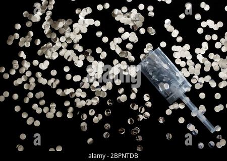 Papier confetti argenté scintillant découpé sur fond noir. Banque D'Images