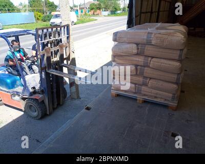 Krasnodar, Russie - 13 juin 2019 : déchargement de sacs de ciment d'un camion avec un chariot élévateur. Banque D'Images