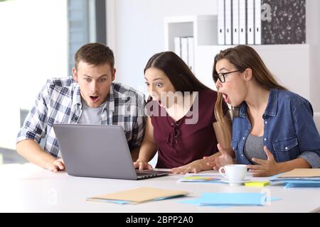 Trois entrepreneurs étonné de recevoir de bonnes nouvelles en ligne à l'office de tourisme Banque D'Images