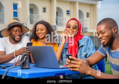 groupe de jeunes amis noirs qui se traînaient dehors, en utilisant différents gadgets de médias, le mode de vie Banque D'Images