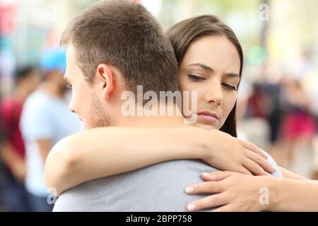 Mécontentement amie hugging her partner dans la rue Banque D'Images